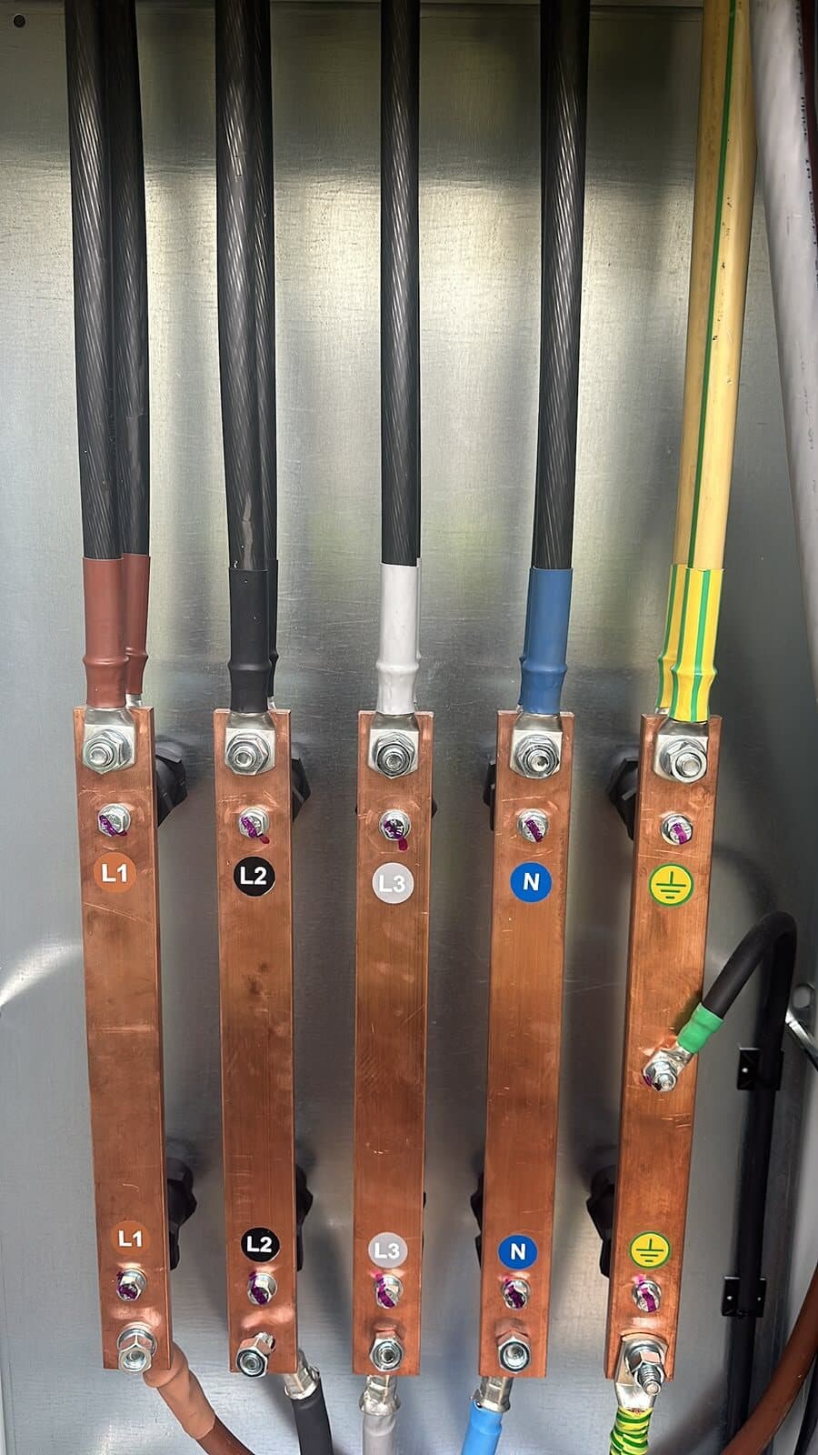 Copper busbars in a low-voltage panel with L1, L2, L3, neutral and earth terminated and labelled