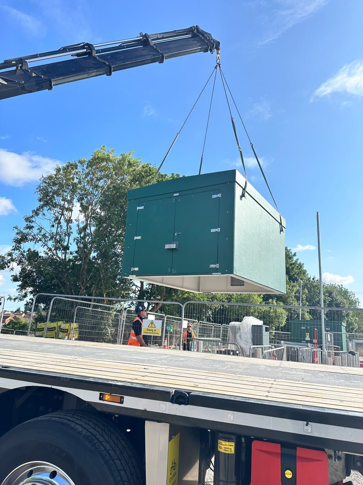 Packaged substation being craned off a lorry bed and lowered onto its base on site
